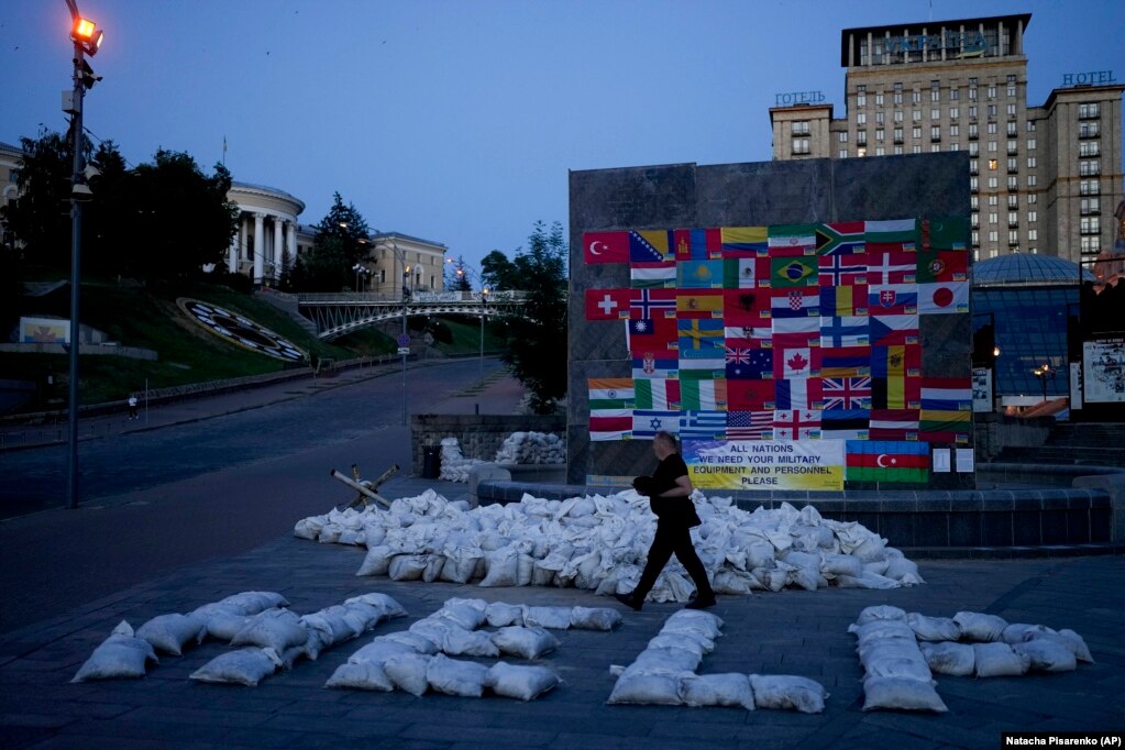 Një burrë duke ecur pranë thasëve me rërë, me të cilët është&nbsp;formuar fjala "Help-Ndihmë", në Sheshin e Pavarësisë, Maidan, në Kiev, më 6 qershor.