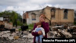 Nila Zelinska plače dok stoji ispred svoje porušene kuće u selu Potašnja, u blizini Kijeva i u rukama drži lutku koja je pripadala njenoj unuki, 31. maja 2022.