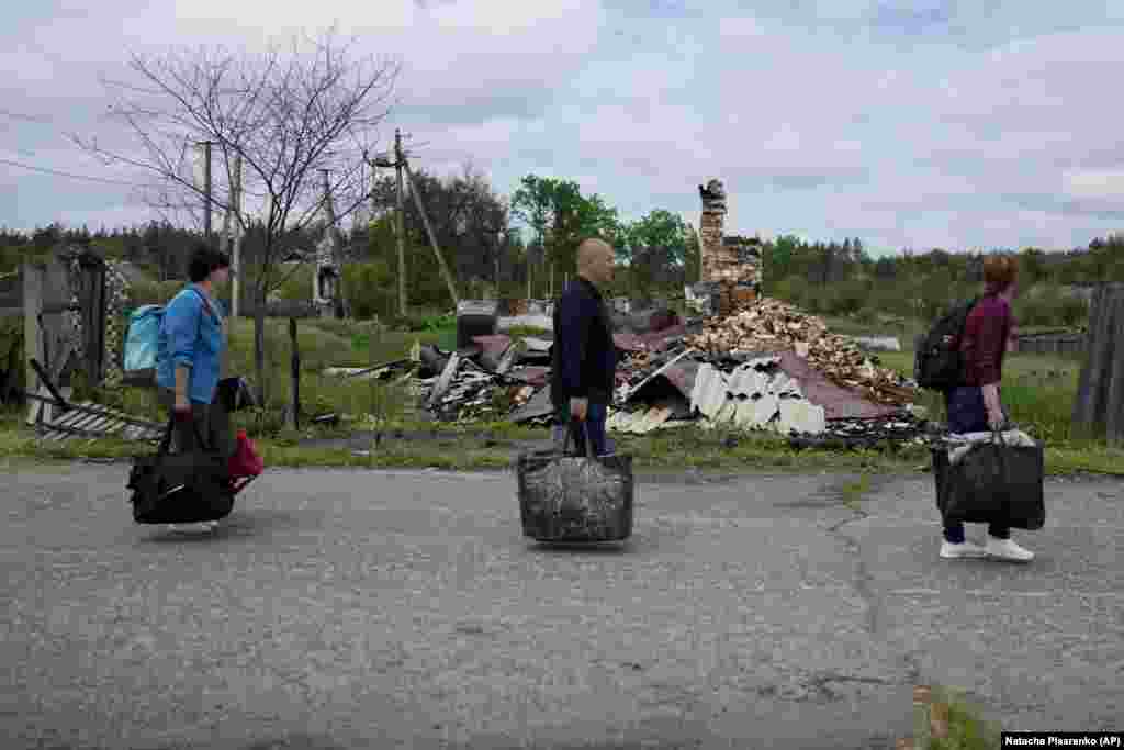 Natalia Didenko,&nbsp;Eduard Zelenskiy, and his wife, Nila Zelinska, walk by destroyed houses on the way to their home in the village of Potashnya, near Kyiv, on May 31. When Russia invaded Ukraine on February 24, it triggered one of the largest humanitarian crises in Europe&#39;s recent history, with an estimated 12.8 million people displaced, most of whom have not left the country.