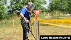 Egy nő aknakereső készüléket használ a koszovói Pejában 2022. május 31-én, ahol ukránok egy csoportját képezik ki taposóaknák és más, fel nem robbant lövedékek eltávolítására