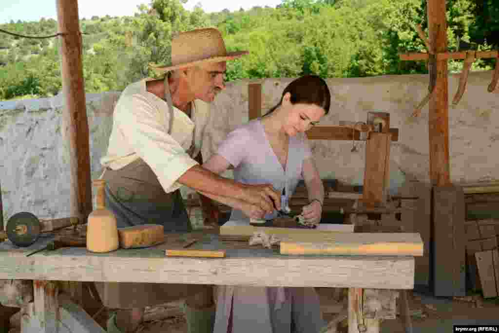 Молодая посетительница пытается работать старинным рубанком, процесс ей нравится