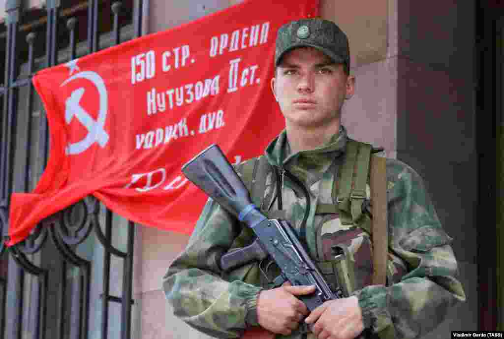 A pro-Russian fighter stands in front of a Communist-era banner that was used to mark Soviet victories over Nazi Germany in World War II. The photo was taken in the eastern Ukrainian town of Svitlodarsk on May 28.&nbsp;