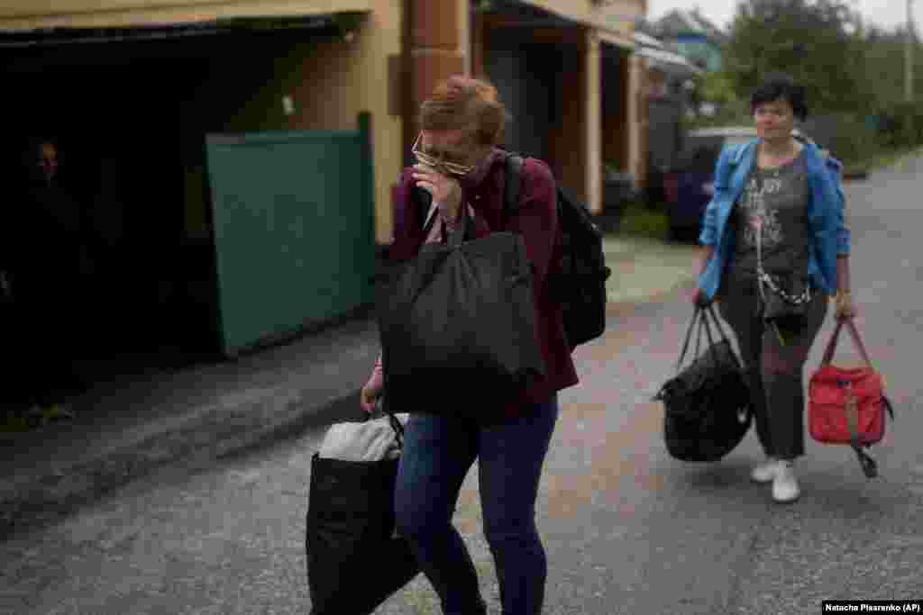 Nila Zelinska (left) cries as she walks to the remains of her house, which was destroyed during Russian attacks.