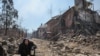 Një burrë struket mes rrënojave në lagjen Livoberezhnyi të Mariupolit të kontrolluar nga Rusia më 6 qershor.