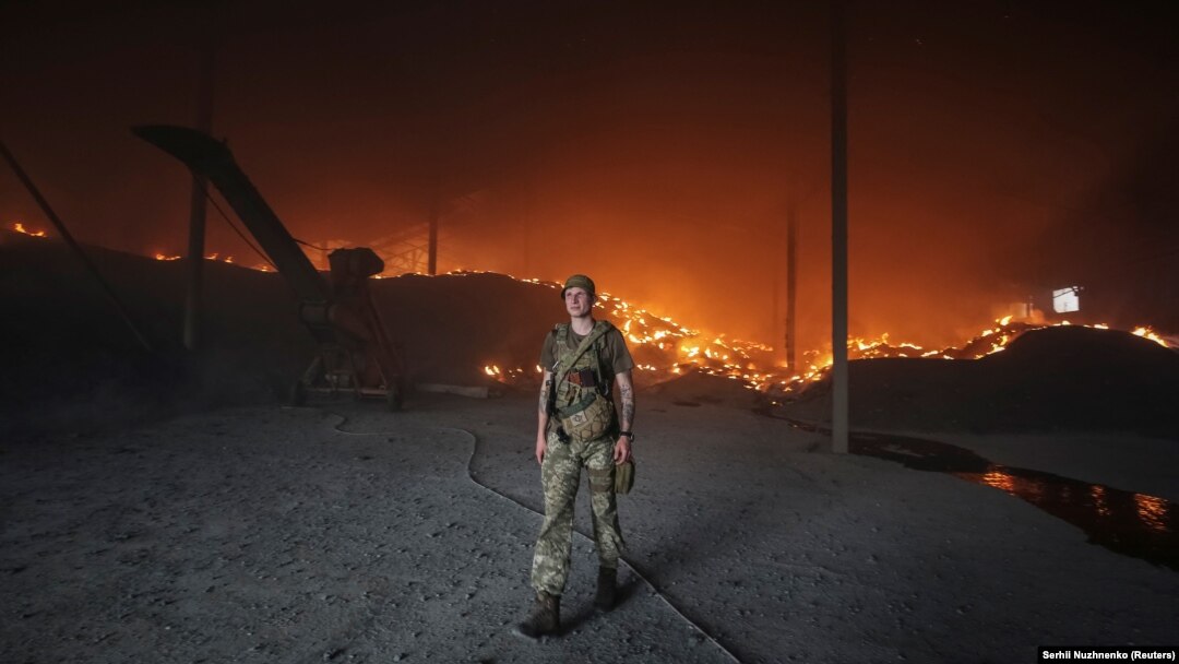 A Ukrainian soldier walks passes a burning grain silo that was shelled repeatedly amid Russia's invasion of Ukraine, in Donetsk region on May 31.
