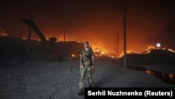 A Ukrainian soldier walks passes a burning grain silo that was shelled repeatedly amid Russia's invasion of Ukraine, in Donetsk region on May 31.
