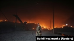 Një ushtar ukrainas duke kaluar pranë një kapanoni të djegur gruri të bombarduar nga forcat ruse, në rajonin e Donetskut më 31 maj.