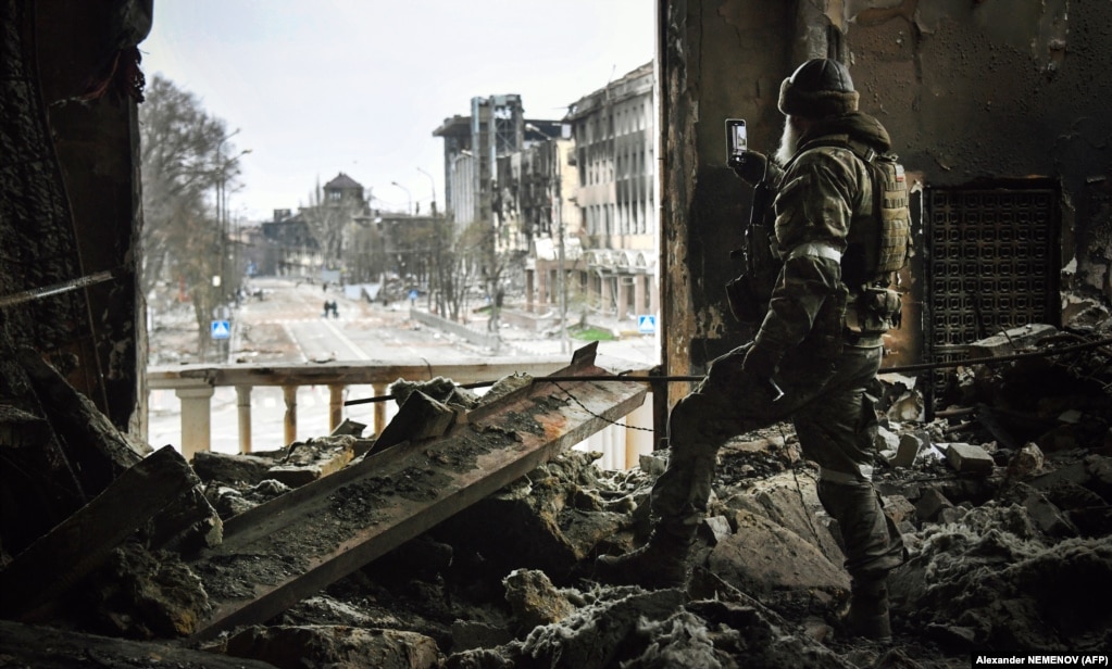 Një ushtar rus shkrep një foto në rrugën kryesore të Mariupol nga teatri i shkatërruar i arteve të qytetit më 12 prill.