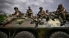 Ukrainian troops sit on an armored vehicle as they move back from the front line near the city of Slovyansk.