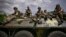 Ukrainian troops sit on an armored vehicle as they move back from the front line near the city of Slovyansk.