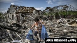 Žena sakuplja stvari nakon što su u napadu uništene tri kuće u gradu Slavjansku u istočnom ukrajinskom regionu Donbasa 1. juna 2022