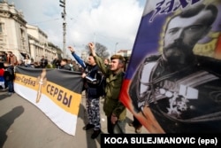 Protesters carry a flag with the picture of Tsar Nicholas II and a banner reading "Serbia" in Serbian and Russian during a demonstration against the NATO in Belgrade in March 2016.