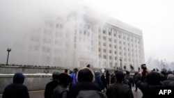 Толпа людей у здания захваченного и подожжённого во время Январских событий акимата Алматы