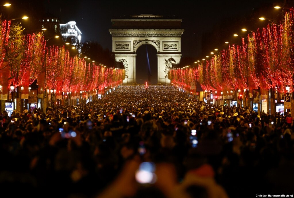 Qytetarët marrin pjesë në festimet për Vitin e Ri në Champs-Elysees të Parisit. Këtë vit, autoritetet anuluan festimet tradicionale me fishekzjarrë dhe drita për shkak të pandemisë së koronavirusit. Paris, 31 dhjetor 2021.   