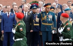Participants, including President Vladimir Putin, Defense Minister Sergei Shoigu, and Prime Minister Dmitry Medvedev, watch honor guards marching past during a wreath-laying ceremony at the Tomb of the Unknown Soldier by the Kremlin wall on Victory Day in 2019.