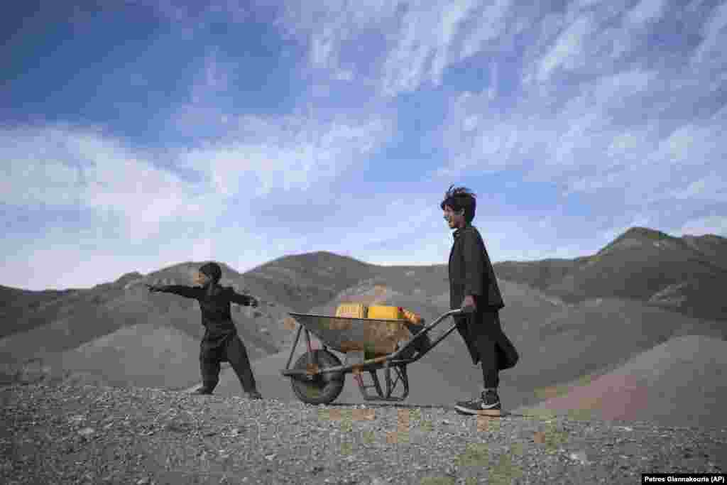 Two brothers carrying canisters with a wheelbarrow react on their way to collect water from a stagnant pool, about 3 kilometers from their home in the village of Kamar Kalagh outside Herat, Afghanistan. Afghanistan&#39;s drought, its worst in decades, is now entering its second year, exacerbated by climate change.