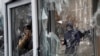 Мужчина фотографирует разбитые окна пункта полиции после протеста в Алматы 