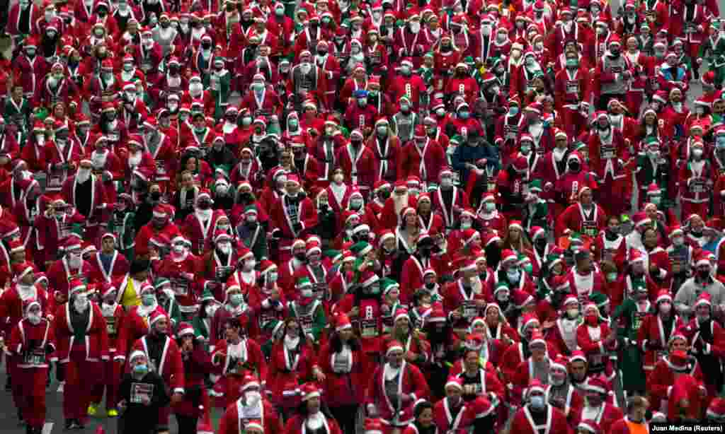 Sute de persoane îmbrăcate în costume de Moș Crăciun participă la o cursă de caritate pentru ajutorarea victimelor erupției vulcanului Cumbre Vieja, în Madrid, Spania.