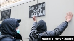 Policajac privodi pristalicu organizacije Memorijal, koju Rusija smatra stranim agentom, ispred moskovskog Vrhovnog suda u decembru 2021. Na natpisu piše: Živjet ćemo uvijek