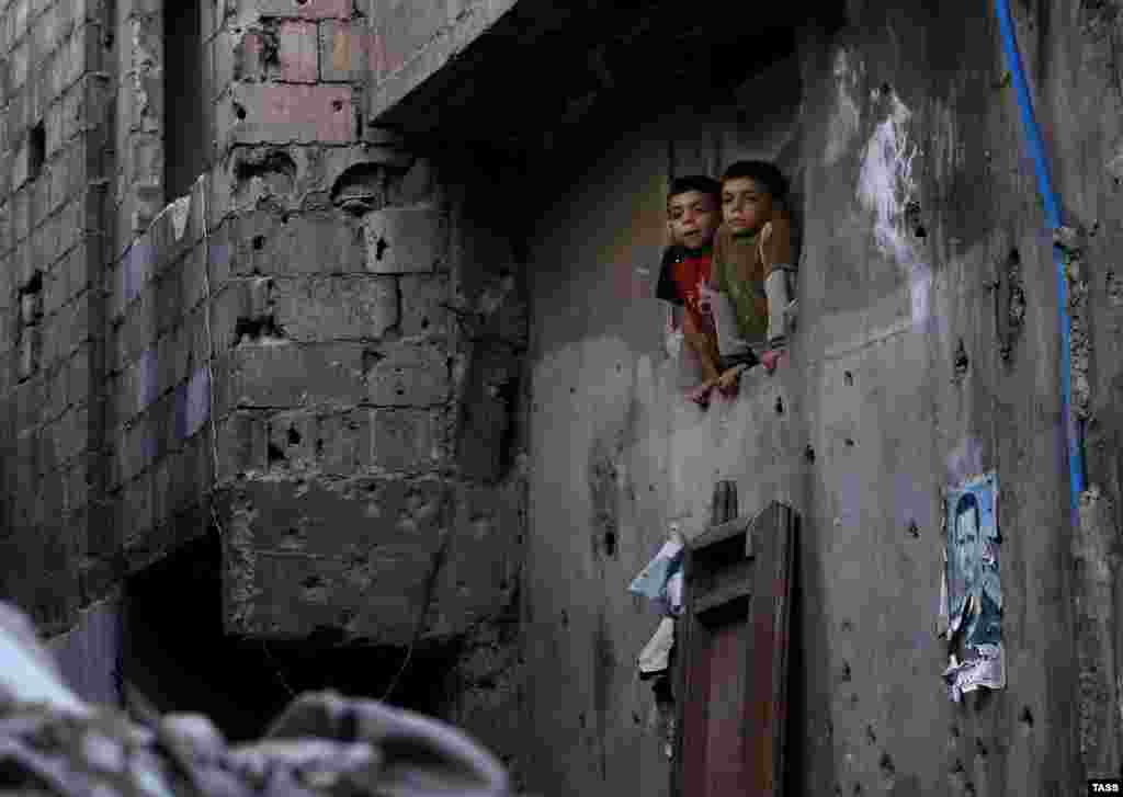 Сирийские дети в окне жилого дома в Дамаске, 19 октября 2015 г.&nbsp;