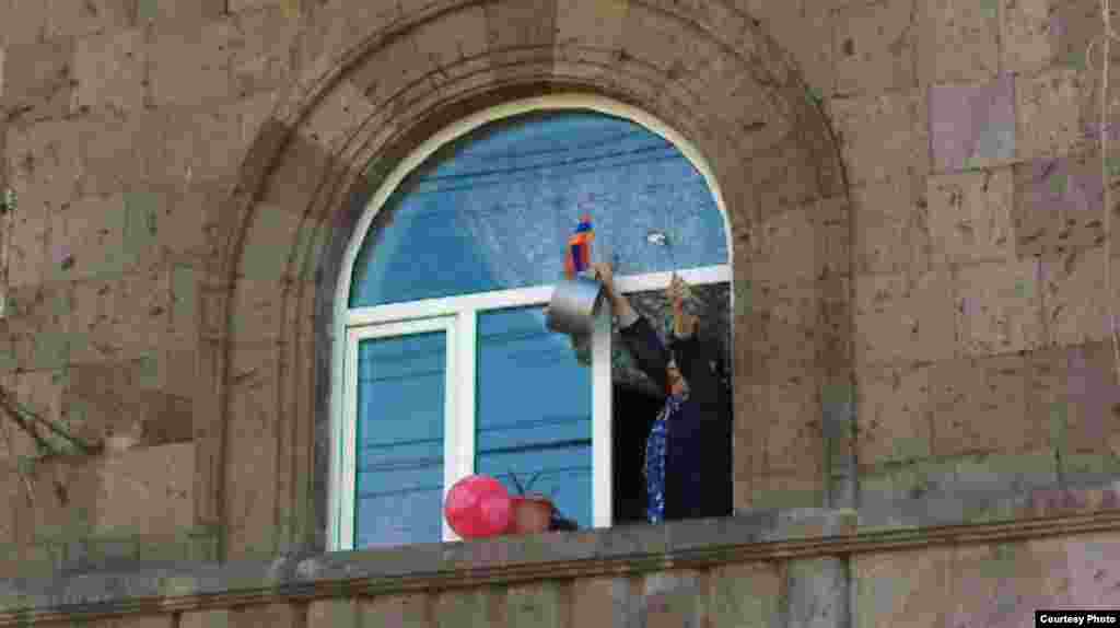 A woman celebrates by banging on a cooking pot at her home in Yerevan.