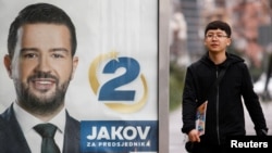 A pedestrian walks past a campaign poster for Jakov Milatovic in Podgoricaahead of the vote.