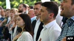 Ukrainian President Volodymyr Zelensky (second right) and participants sing the national anthem during his Servant of the People party's conference before the recent parliamentary elections. Many of the candidates chosen at this event will now be entering parliament for the first time. 