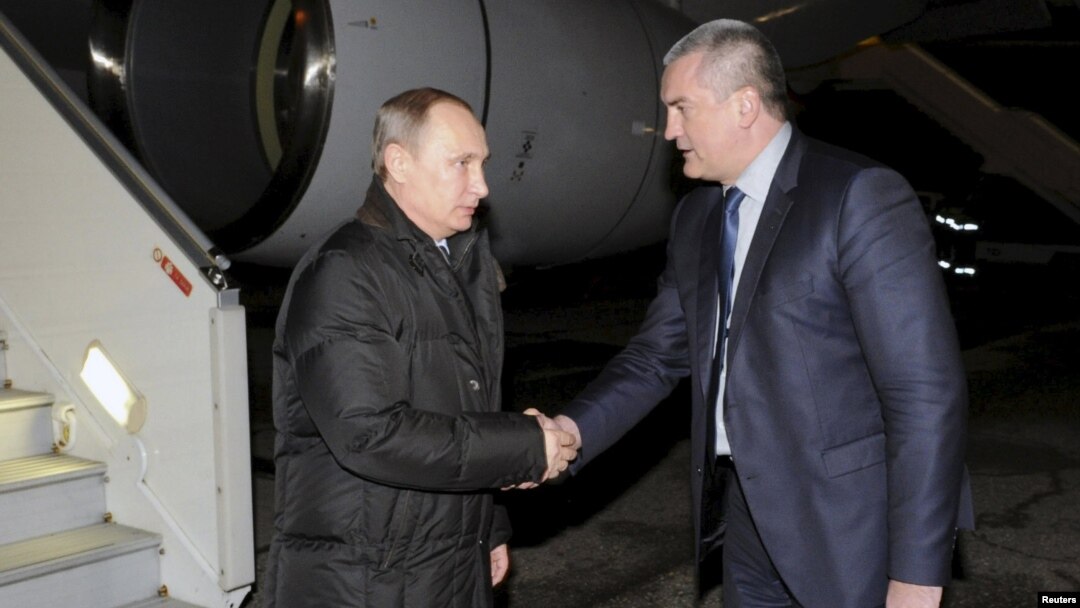 Russian President Vladimir Putin (left) shakes hands with Sergei Aksyonov, the de facto prime minister of the annexed Ukrainian peninsula, upon the former's arrival at Simferopol airport on December 2.