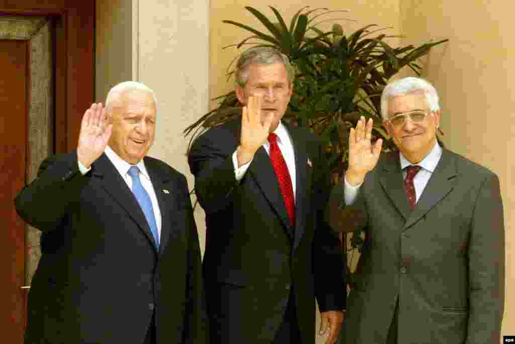 Jordan -- US President George W. Bush (C), Israel's Prime Minister Ariel Sharon (L) and Palestinian Prime Minister Mahmoud Abbas wave at the media at the royal palace in the jordanian town of Aqaba, 04Jun2003