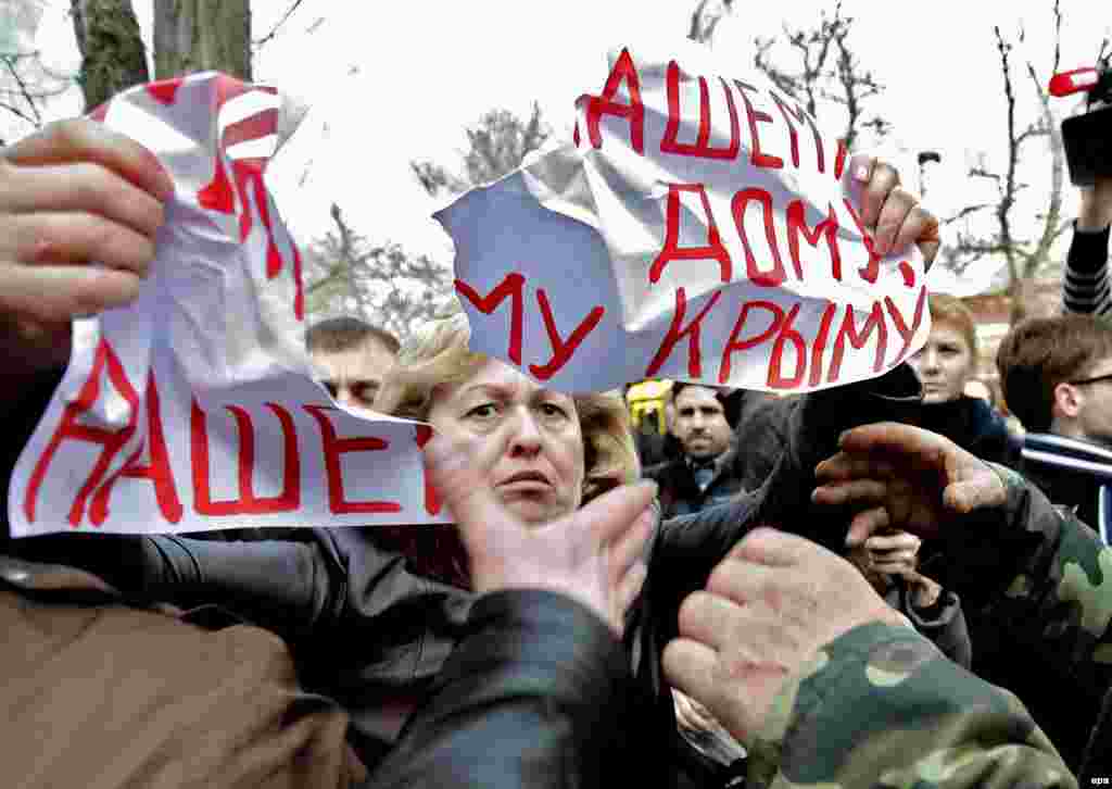 Unidentified men tear apart a placard reading &quot;Peace for our home, our Crimea!&#39;&quot; that a woman holds during a protest against war in Simferopol, Crimea, on March 5. (epa/Anastasia Vlasova)