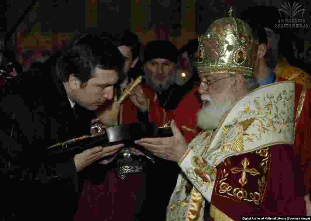 ილია მეორე და მიხეილ სააკაშვილი, საქართველოს პრეზიდენტი 2004--2013 წლებში. ფოტო გადაღებულია გელათის მონასტერში. 2004 წლის საპრეზიდენტო ინაუგურაციაზე სააკაშვილი პრეზიდენტად სიმბოლურად სწორედ ილია მეორემ აკურთხა. 