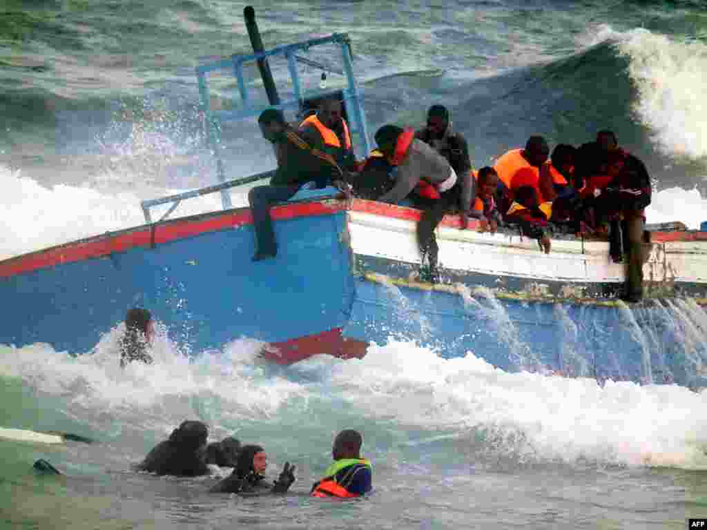 Rescuers help people in the sea after a boat carrying some 250 migrants crashed into rocks as they tried to enter the port of Pantelleria, an island off the southern coast of Italy, on April 13. A fishing boat that had sailed across the Mediterranean from Libya ran aground on rocks on Pantelleria, killing two women. Italy is struggling to cope with a mass influx of immigrants from North Africa, many of whom risk their lives by sailing across the often stormy Mediterranean in makeshift vessels. Photo by Francesco Malavolta for AFP