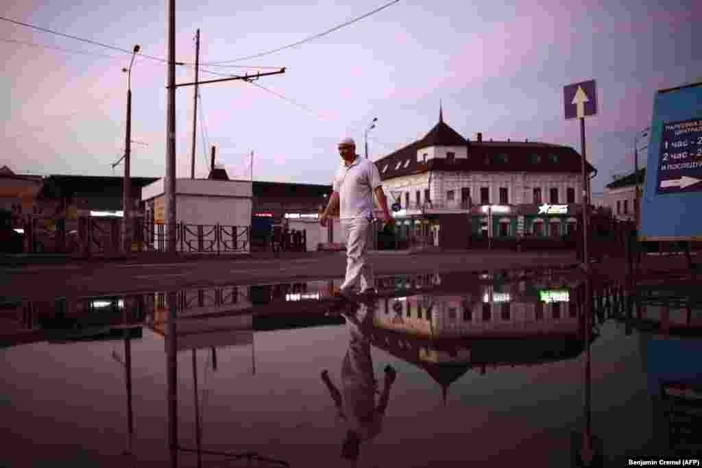 A man crosses a flooded street after a storm at sunset in Kazan on June 26. (AFP/Benjamin Cremel)