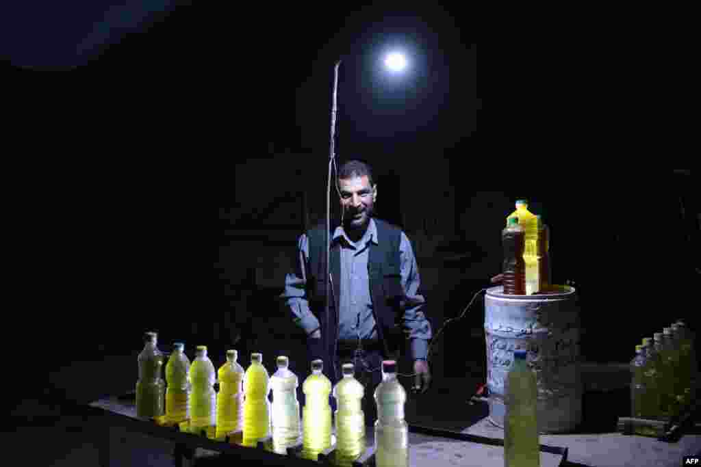 A Syrian street vendor selling fuel uses a battery-powered lamp to light his stall at night in the rebel-held area of Douma, east of the capital Damascus, on April 27.&nbsp;