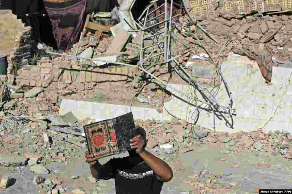 A man retrieves a copy of the Koran from the debris of Al-Hussein Mosque following an explosion in the district of Al-Musayyib, south of Baghdad. (AFP/Ahmad Al-Rubaye)