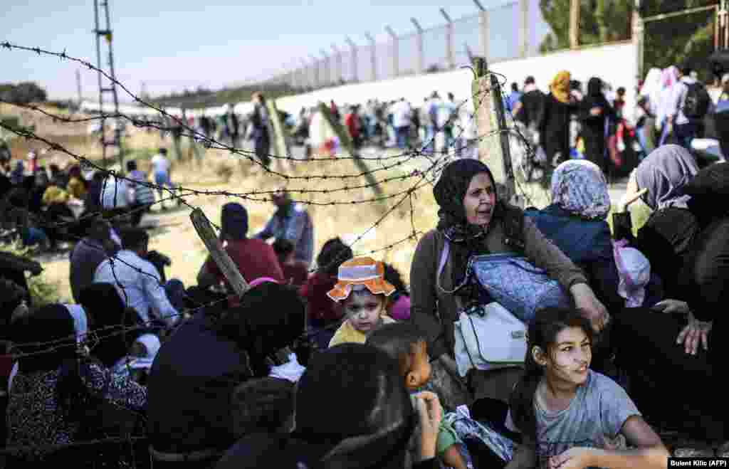 Syrian refugees wait at the Oncupinar crossing gate, close to the town of Kilis, in south-central Turkey, before crossing into Syria for the Eid al-Adha Muslim holiday. Turkish authorities allow Syrian refugees to visit their country for the festivities. (AFP/Bulent Kilic)