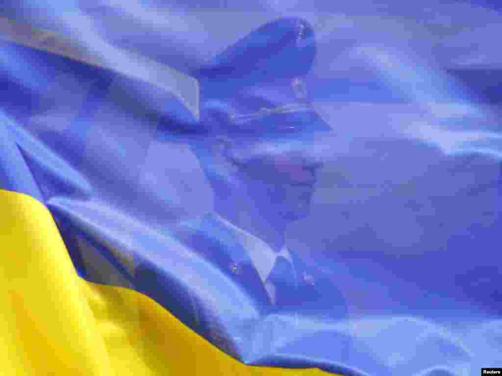 An honor guard is seen through the Ukrainian flag during a ceremony welcoming Sri Lankan President Mahinda Rajapaksa to Kyiv on June 30. Photo by Gleb Garanich for Reuters