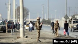Afghan security personnel stand guard at the site of explosions in front of the Kabul Military Training Center in Kabul on November 18.
