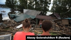 Local residents are seen near the debris of houses destroyed by floods in the town of Tulun in the Irkutsk region earlier this month.