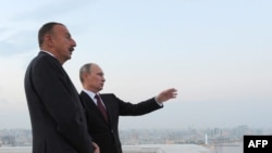 Azerbaijan -- Russia's President Vladimir Putin (L) and his Azerbaijani counterpart Ilham Aliyev (R) speak as they walk in Baku, on August 13, 2013.