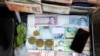 Iranian bills stacked in a briefcase with a few gold coins in a currency exchange service in Tehran, Iran, 22 June 2020. 