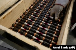 A Bosnian worker places empty munitions into a box.