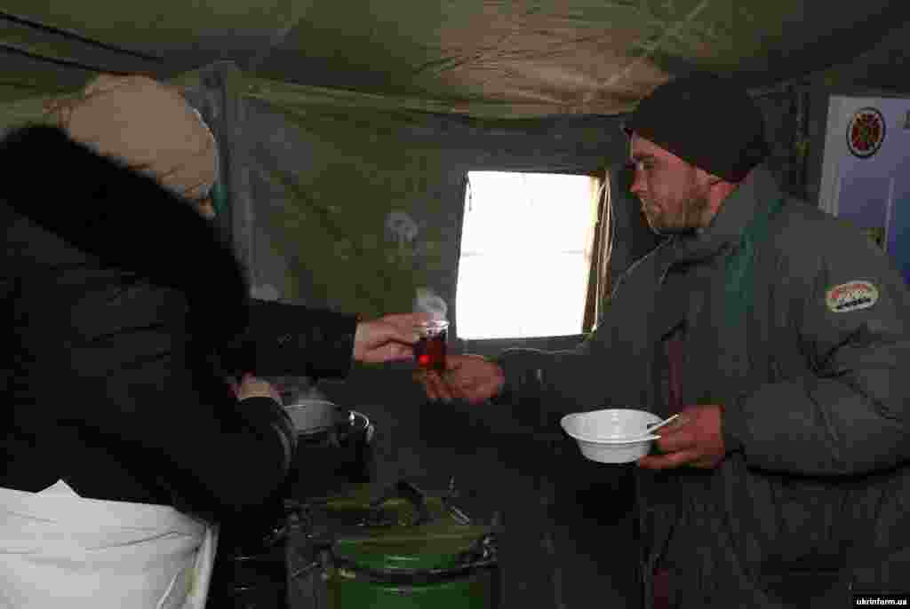 Жінка дає чоловіку гарячий чай в одному з мобільних пунктів обігріву Дніпропетровська, 4 січня 2015 року