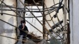 KAZAKHSTAN -- A woman speaks on a mobile phone as she removes debris from a burnt out building in the majority-Dungan village of Masanchi - in southern Kazakhstan's Jambyl region close to the border with Kyrgyzstan - on February 12, 2020. - Life in Centra