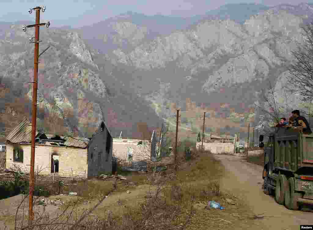 Ethnic Armenians in a truck pass houses destroyed in the recently built ethnic-Armenian settlement of Knaravan before control of the Karvachar/Kalbacar district is returned to Azerbaijan.