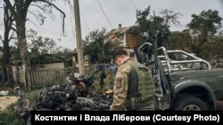 Një ushtar i pikëlluar shikon rrënojat e një automjeti, në të cilin një shok i tij u vra nga zjarri i forcave ruse.