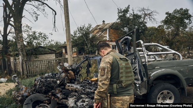 Një ushtar i pikëlluar shikon rrënojat e një automjeti, në të cilin një shok i tij u vra nga zjarri i forcave ruse.