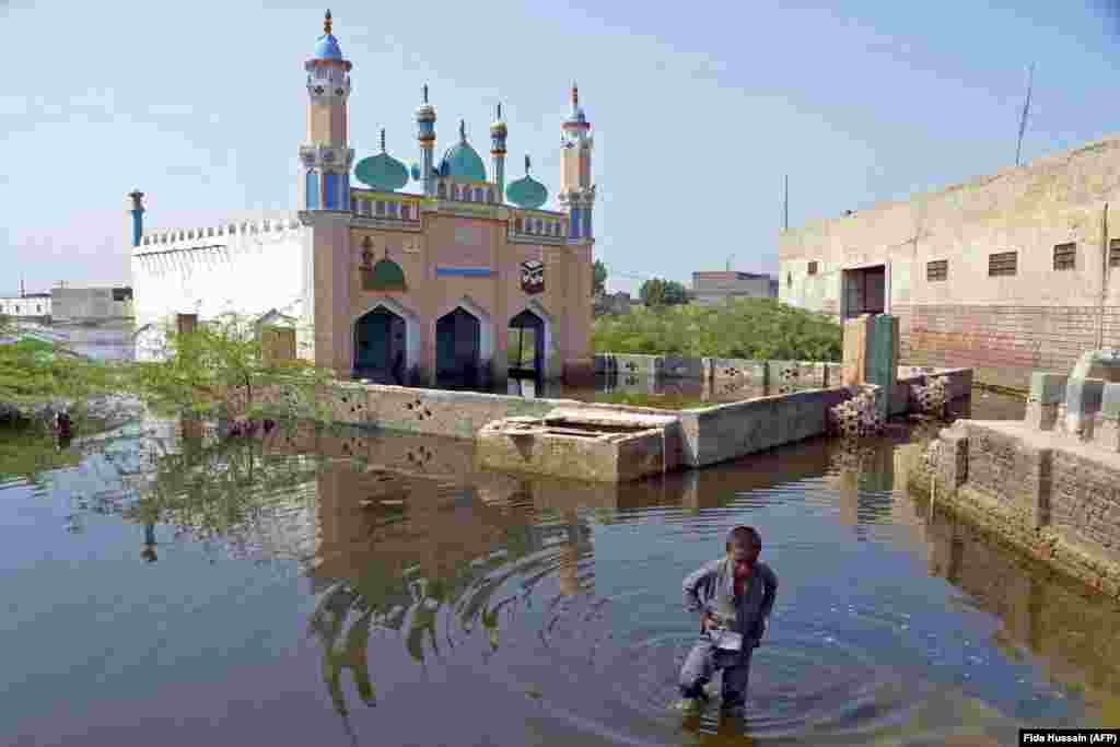 A boy wades through floodwaters in the Jaffarabad district in central Pakistan on September 19. The 2022 monsoon season has dumped more than three times the average rainfall on Pakistan, leading to vast swaths of the country being submerged.&nbsp; &nbsp;