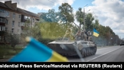 Ukrainian soldiers on an armored fighting vehicle drive through the recently liberated town of Kupyansk in the Kharkiv region in an image released on September 19.