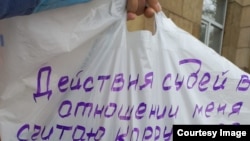 Жительница Темиртау Сания Зверева держит пластиковый пакет с призывом отправить в отставку нескольких судей